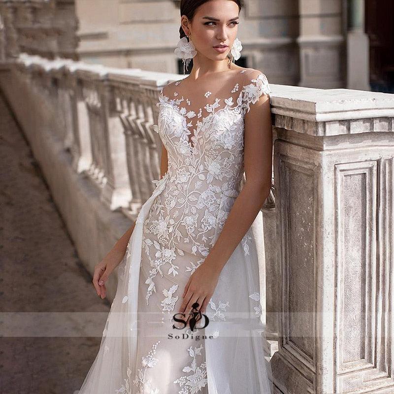 Vestido de novia NumberSea 2021 de manga corta con apliques, corte sirena y cola desmontable sobre falda de encaje.