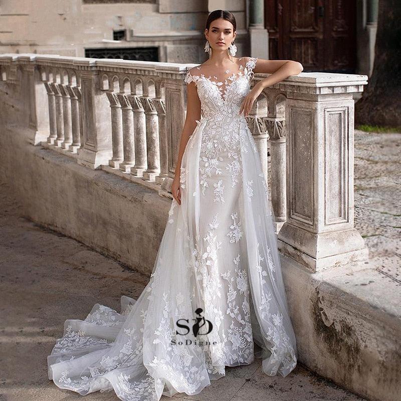 Vestido de novia NumberSea 2021 de manga corta con apliques, corte sirena y cola desmontable sobre falda de encaje.
