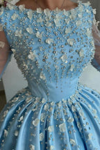 Elegante vestido de fiesta largo azul cielo de satén con pedrería y mangas largas.